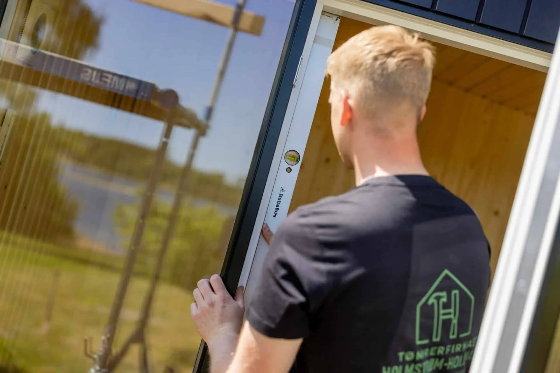 Tømrer monterer en karm med vaterpas